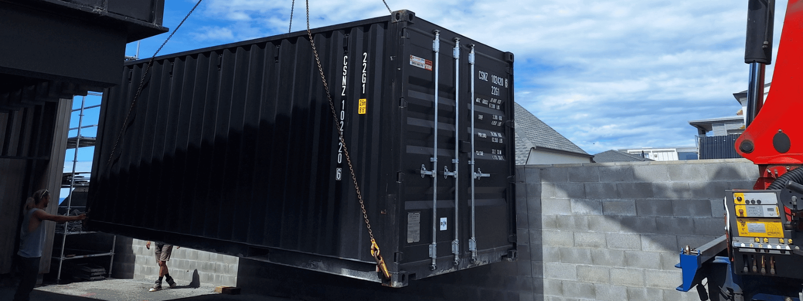A new black 20-foot shipping container is being craned into a tight space for a customer in New Zealand.