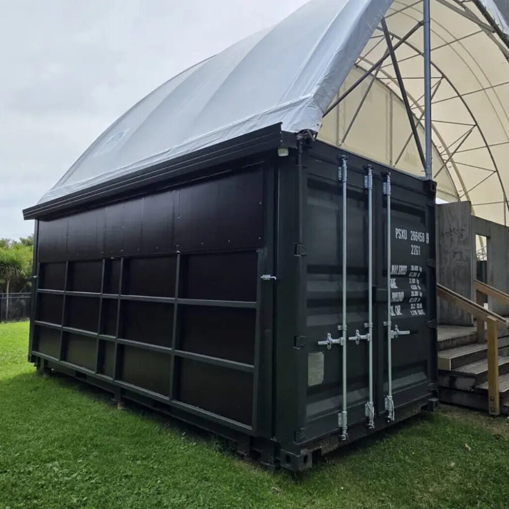 Black shipping container under a dome canopy shelter